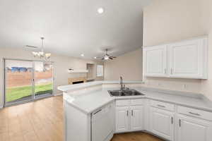 Kitchen featuring sink, white dishwasher, white cabinets, and decorative light fixtures