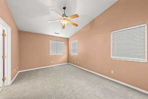 Carpeted spare room with lofted ceiling and ceiling fan