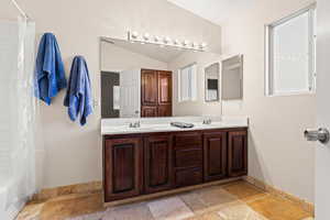 Bathroom with vaulted ceiling, shower / bath combination with curtain, and vanity