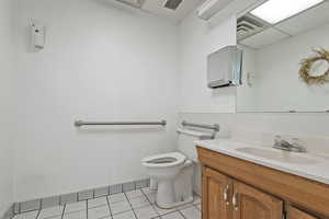 Bathroom with toilet, tile patterned floors, and vanity