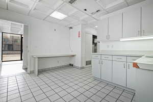 Kitchen featuring coffered ceiling, white cabinetry, and light tile patterned floors