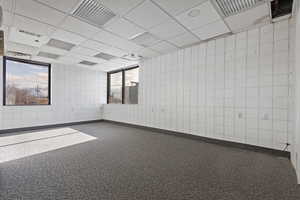 Unfurnished room with a drop ceiling and carpet floors