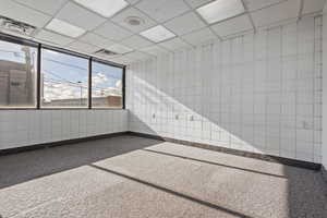 Carpeted empty room featuring a drop ceiling