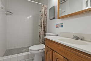 Bathroom featuring tile patterned flooring, toilet, vanity, and walk in shower