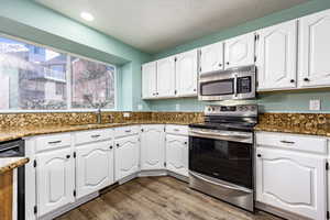 Kitchen with white cabinets, dark stone counters, and appliances with stainless steel finishes