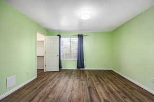 Spare room with dark wood-type flooring and a textured ceiling