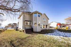 Snow covered back of property featuring central air condition unit, a playground, and a yard