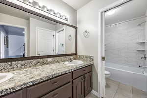 Full bathroom featuring vanity, toilet, tiled shower / bath, and tile patterned floors