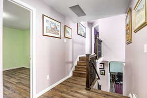 Stairway featuring wood-type flooring and a textured ceiling