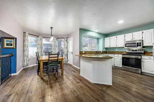 Kitchen featuring appliances with stainless steel finishes, sink, white cabinets, a textured ceiling, and dark hardwood / wood-style floors