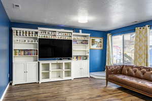 Living room with a textured ceiling and dark hardwood / wood-style flooring