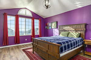 Bedroom with hardwood / wood-style flooring, multiple windows, lofted ceiling, and a textured ceiling