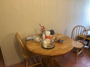 Dining space featuring tile patterned flooring and wooden walls