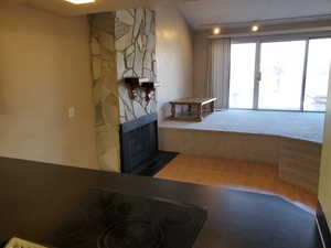 Interior space featuring hardwood / wood-style flooring, a stone fireplace, and lofted ceiling