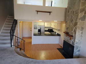 Kitchen featuring a towering ceiling, a fireplace, sink, stainless steel fridge, and carpet flooring