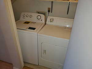 Washroom featuring light tile patterned flooring and washing machine and dryer