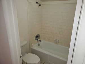 Bathroom with tile patterned floors, toilet, and tiled shower / bath