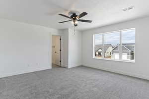 Empty room featuring carpet floors, a textured ceiling, and ceiling fan