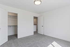 Unfurnished bedroom featuring a spacious closet, a closet, and carpet floors