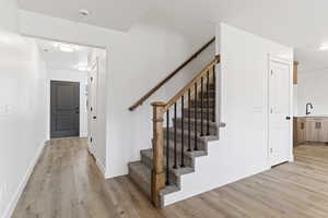 Stairway featuring wood-type flooring and sink