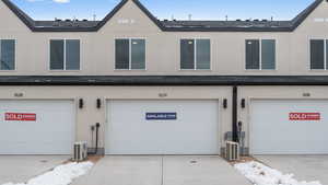 View of property with a garage and ac unit