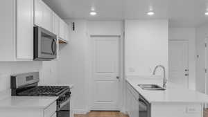 Kitchen featuring sink, white cabinets, light hardwood / wood-style flooring, and stainless steel appliances