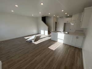 Kitchen with sink, white cabinets, dark hardwood / wood-style flooring, and an island with sink