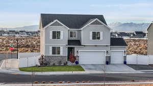 View of front facade with a garage, a mountain view, and a front yard