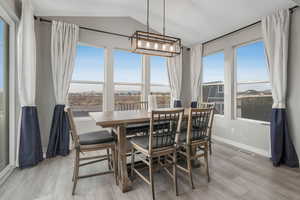 Dining area with vaulted ceiling and light wood-type flooring