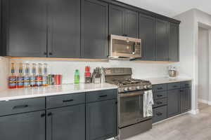 Kitchen featuring backsplash, light wood-type flooring, gray cabinetry, and appliances with stainless steel finishes