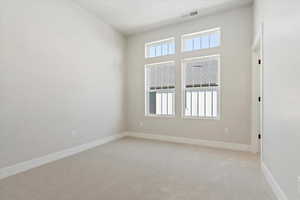 Unfurnished room with a high ceiling and light colored carpet