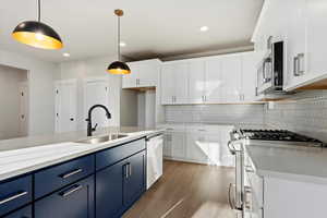 Kitchen with sink, hanging light fixtures, blue cabinetry, and appliances with stainless steel finishes