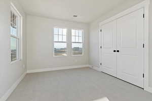 Unfurnished bedroom featuring light colored carpet and a closet