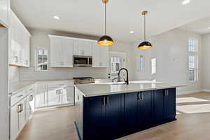 Kitchen with sink, pendant lighting, appliances with stainless steel finishes, and an island with sink