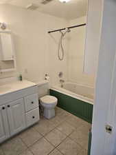 Full bathroom featuring toilet, a textured ceiling, tiled shower / bath combo, and vanity