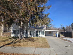 View of front facade featuring a front lawn and a carport