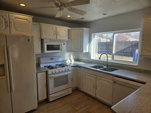 Kitchen featuring hardwood / wood-style floors, ceiling fan, white appliances, a textured ceiling, and sink