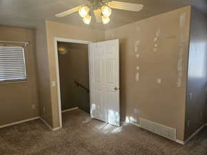 Primary bedroom with ceiling fan, a closet, and dark carpet