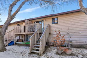 Snow covered rear of property with a deck