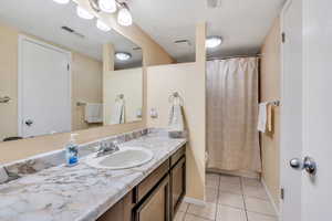 Bathroom with vanity, toilet, tile patterned floors, and a textured ceiling