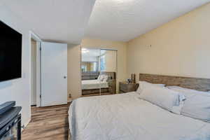 Bedroom featuring wood-type flooring, a textured ceiling, and a closet