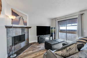 Living room with hardwood / wood-style flooring, a textured ceiling, and a fireplace