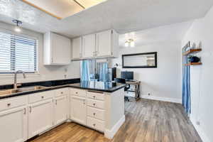 Kitchen featuring sink, white cabinets, light hardwood / wood-style flooring, and kitchen peninsula