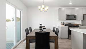 Dining area with light hardwood / wood-style floors and a notable chandelier