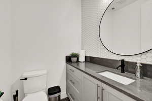 Bathroom featuring tasteful backsplash, toilet, and vanity