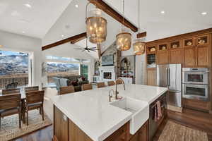 Kitchen with decorative light fixtures, high vaulted ceiling, dark wood-type flooring, stainless steel appliances, and a center island with sink