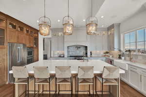 Kitchen with decorative light fixtures, sink, backsplash, a large island, and high end fridge