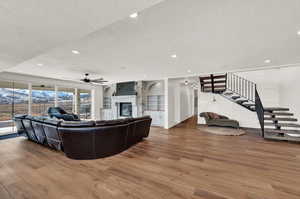 Living room with a textured ceiling, hardwood / wood-style floors, built in shelves, a fireplace, and ceiling fan