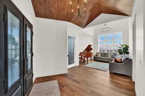 Foyer featuring a notable chandelier, light hardwood / wood-style floors, wood ceiling, french doors, and vaulted ceiling