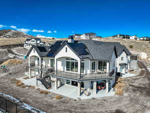 Rear view of house featuring a balcony, a mountain view, and solar panels